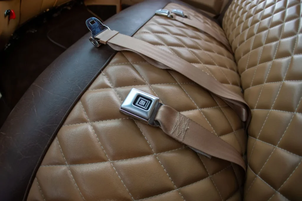 Seatbelt buckle across a diamond-stitched tan bench seat
